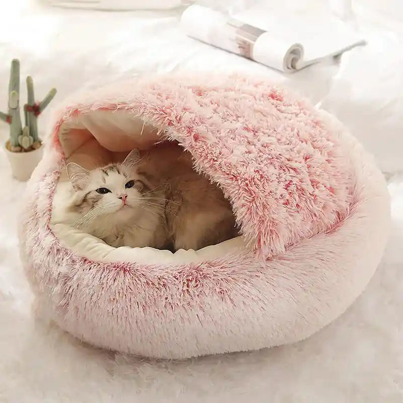 Cat relaxing in pink fluffy winter bed.