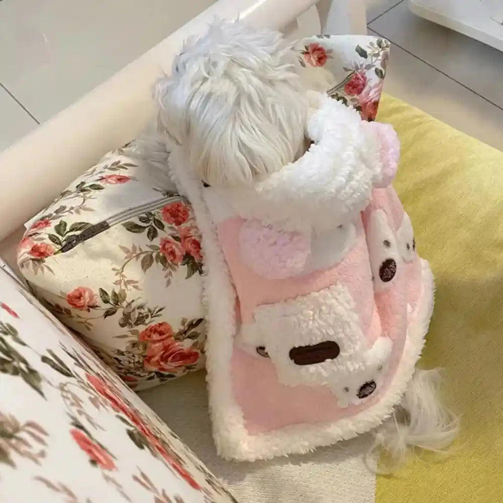 White dog in pink bear cape on floral cushion